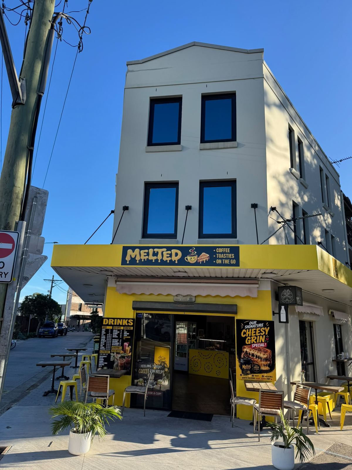 Redfern NSW three-storey corner mixed-use building with ground-floor cafe and dark-framed windows