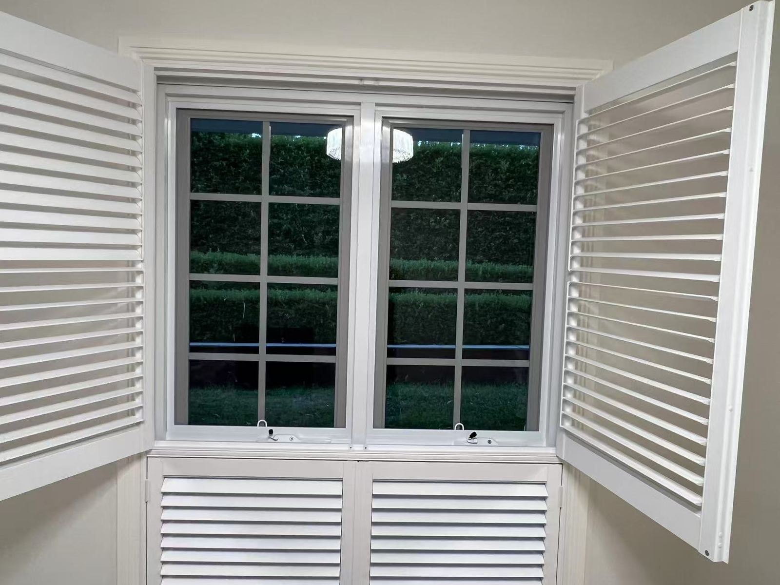 Interior view of white double-hung windows with grid bars and shutters